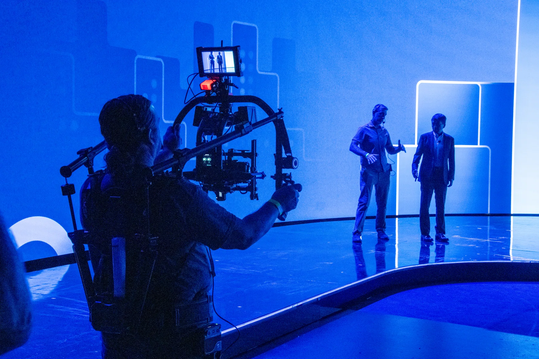 Zoomtopia camera operator filming presenters on a blue rehearsal stage